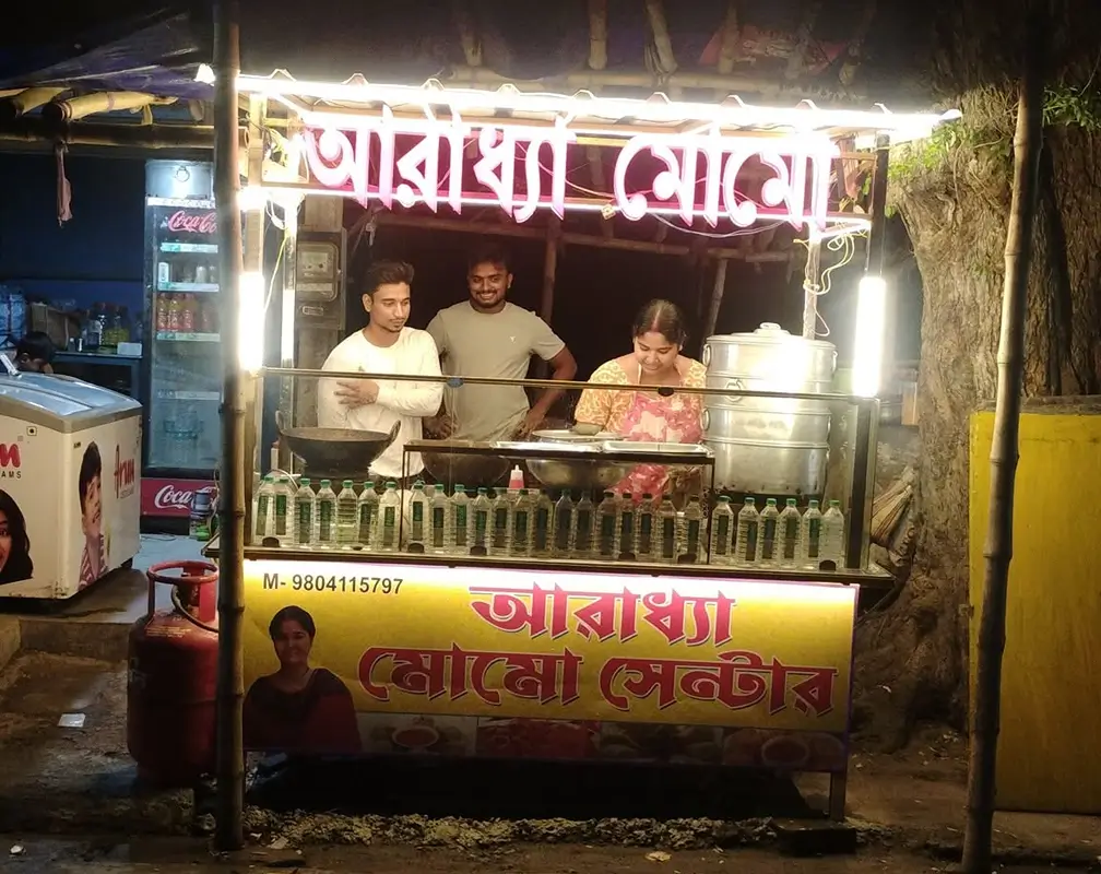 Evening momo stall with warm string lights and steaming bamboo baskets